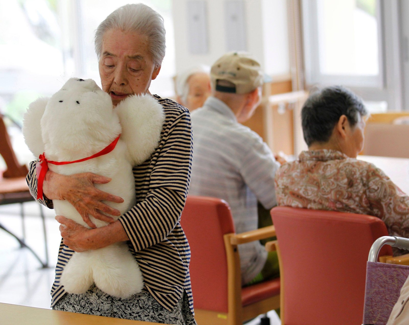 Satsuko Yatsuzaka (84 ans) tient un robot thérapeutique nommé Paro à la maison de retraite Suisyoen.