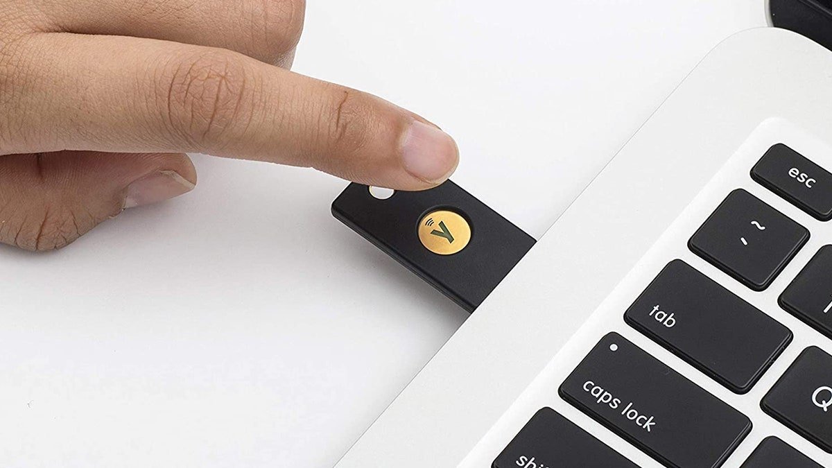 Gros plan du doigt d'une personne touchant la YubiKey branchée sur un ordinateur portable