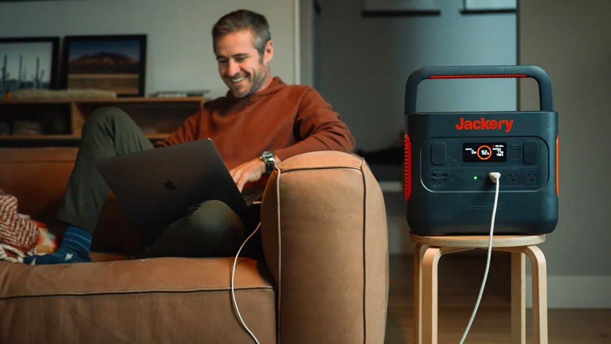 Personne assise sur un canapé en chargeant un Macbook avec la batterie Jackery