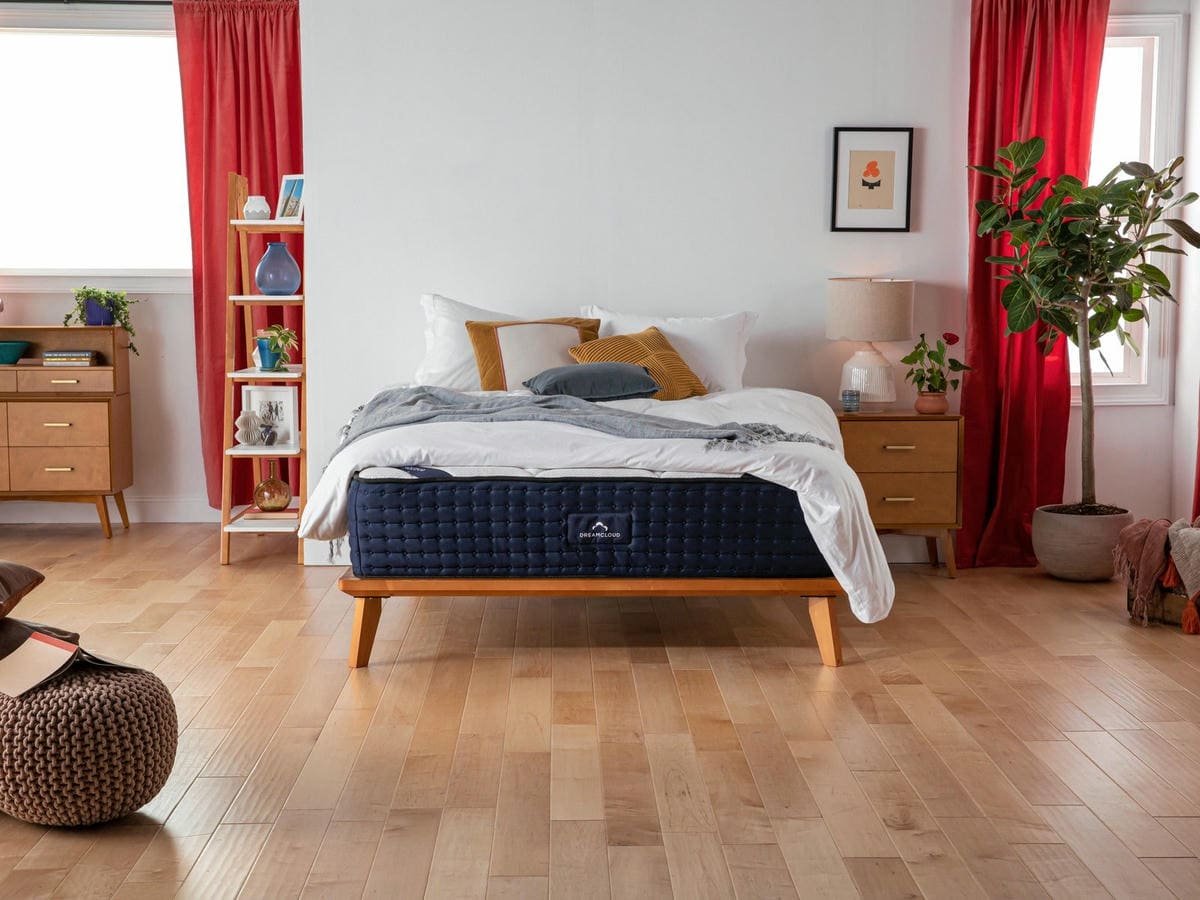 Matelas hybride Dreamcloud sur un cadre de lit dans un salon moderne