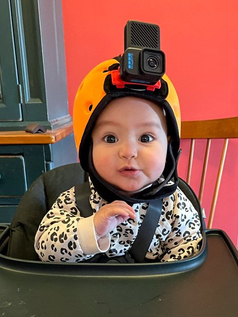 bébé portant une caméra sur la tête assis sur une chaise haute