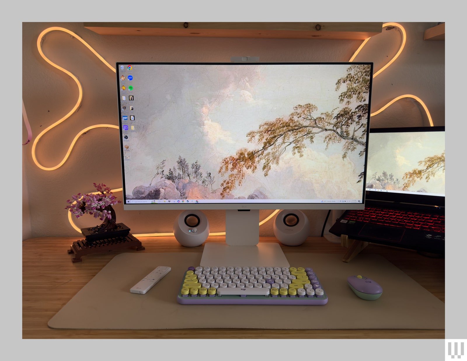 Moniteur à écran plat blanc sur le bureau avec 2 haut-parleurs de chaque côté, éclairage au néon derrière et image du ciel et des feuilles...